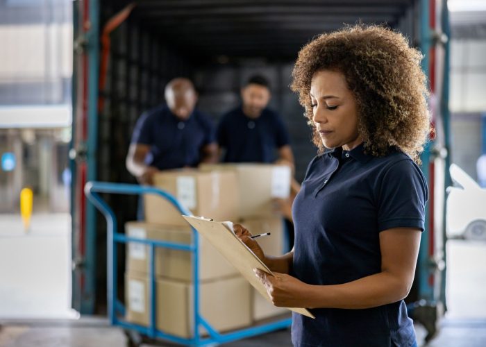 African American woman supervising the shipping of cargo at a distribution warehouse - freight transportation concepts